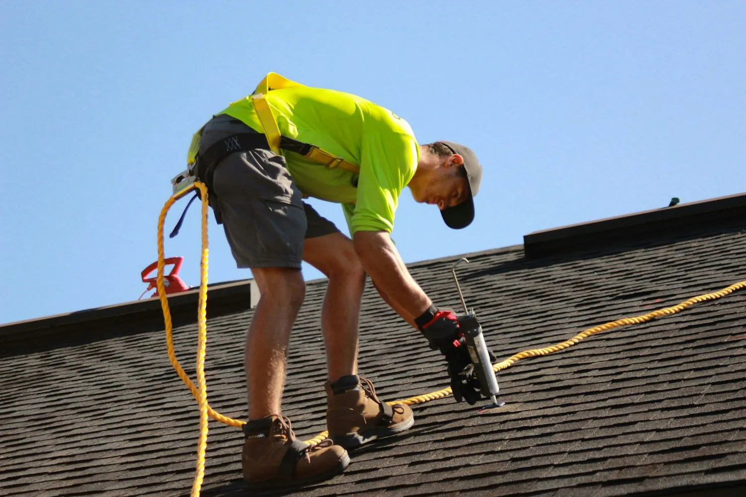 An Anchor Roofing installer securing architectural shingles on a residential roof